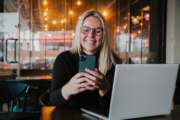 Young influencer in front of the laptop working in the cafe indoors . SMM manager.