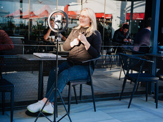 Young influencer in front of the camera and selfie ring light reading a text . SMM manager.