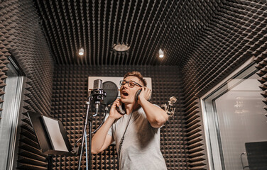 The vocalist sings in the studio in a microphone. Man in headphones writes a podcast, an audiobook....