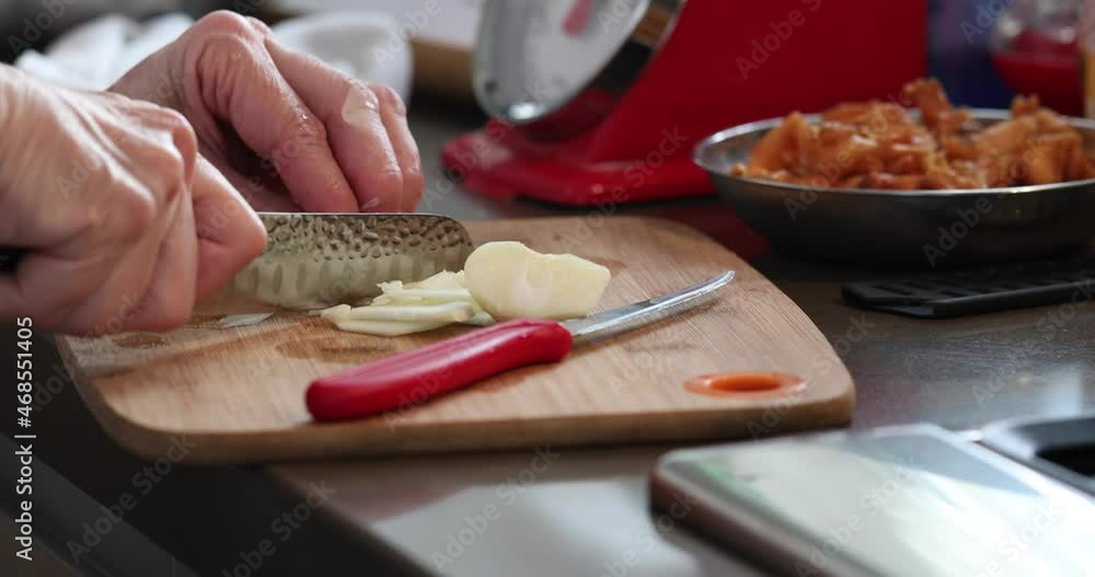 Wall mural Chef cuts onions on wooden board in the kitchen