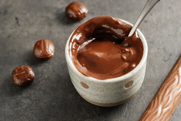 Melting chocolate in cup on dark background
