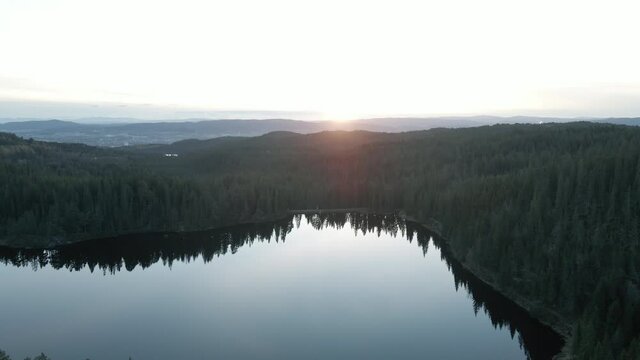 Calm Waters Of Lake Surrounded With Coniferous Forest At Sunrise. - aerial