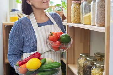Obraz premium Middle aged woman with food in the pantry in the kitchen