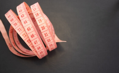 pink measure tape isolated or in woman hand. metric scale. curly circle shape soft tape for sewing.body measurement fitness weight loss concept, space for text advertising banner.snowflake wooden eco 