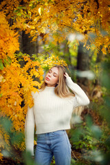 beautiful autumnal young girl in a white sweater in the park among the trees, caucasian girl with beautiful long hair and full lips, portrait of a girl soft focus and beautiful bokeh
