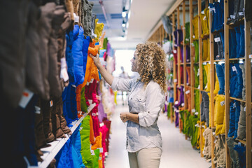 Adult woman in decorations house shop store choosing colorful pillows. Variety of products and shopping at the mall people activity concept