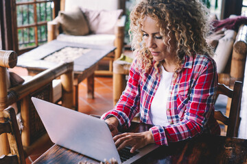 One adult woman at home working on laptop on the table. Modern hipster female people in online job...