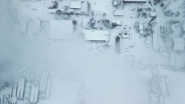Flight over the industrial zone to the pipe of the heat power network with a loading dock with frozen water in ice. Plumes of smoke against the background of the city.