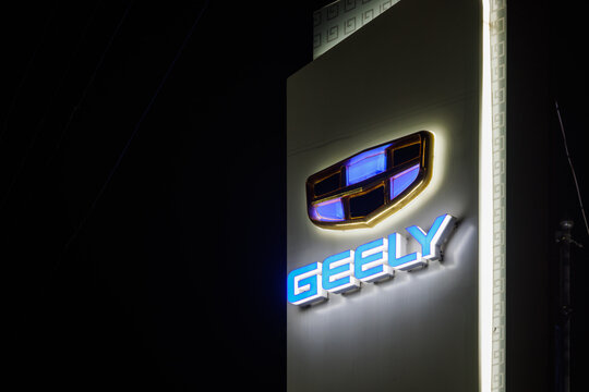 Geely logo on car dealership pillar at foggy night - Geely is one of the largest Chinese automobile manufacturer