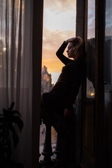 Fototapeta na wymiar Beautiful young woman near the window on sunset. City view