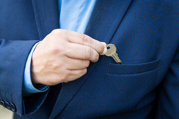 Businessman in a business suit with private house key in the pocket. House and keys, the idea of...