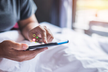 Young woman playing with smartphone while laying on bed.  Asian girl relaxing on bed and playing metaverse with the mobile phone.
