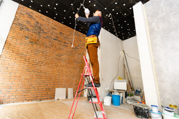 Electrician repairing ceiling light, working