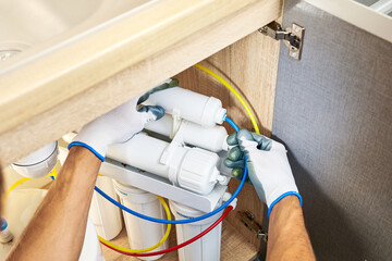 Technician installing or repairing system of water filtration. Plumber hand in gloves replace water...