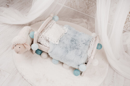 Newborn baby bed with a little sheep in a photo studio