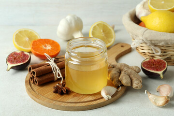 Concept of treatment colds with honey and garlic on white textured background