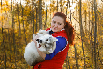The dog breeder is hugging with her husky dog in autumn forest