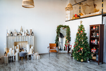 Interior shot. Two-storey room with fireplace, decorated Christmas tree, preparations for the new year Modern apartment. Red staff