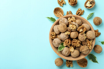 Walnuts in wooden bowl on blue background