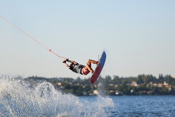 Teenage wakeboarder doing trick over river. Extreme water sport