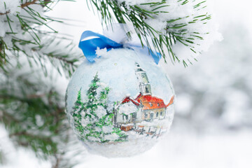 A colorful Christmas ball hung on a snow-covered Christmas tree twig 