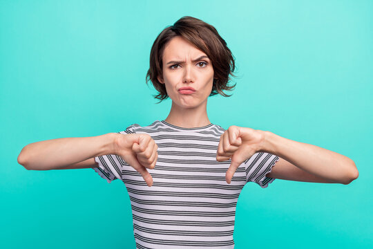Photo of young girl unhappy upset show thumb-down bad quality dislike isolated over teal color background