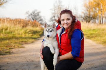 The dog breeder is hugging with her husky dog in autumn forest - 468566006