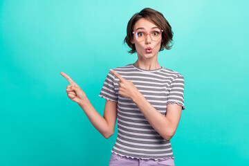 Photo of young girl amazed shocked indicate fingers empty space advertise choose isolated over turquoise color background