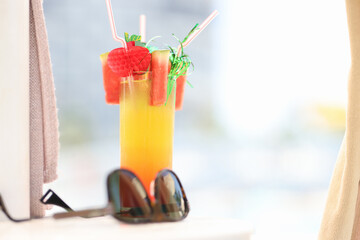 Sunglasses lying near alcoholic cocktail glass on beach closeup