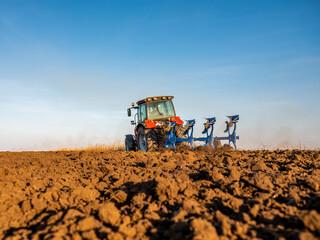 Fototapeta premium Farmer in tractor plowing preparing stubble field cultivating for seeding crops.
