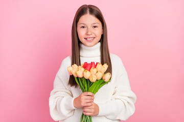 Portrait of attractive cheerful cute girl holding in hands tulips mom day isolated over pink pastel color background