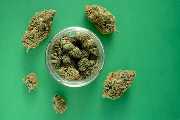 Close up of cbd cannabis buds in glass jar, macro view. Medicinal marijuana blooms on emerald green...