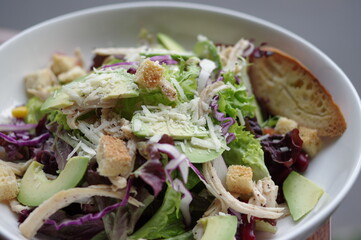 salad with avocado, chicken breast and bread top view 