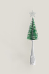 2022 Baby bottle cleaning brush like a green Christmas tree with a silver star on a top. Minimal abstract winter New Years scene isolated on beige background. Greeting card or gift card idea.