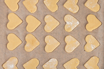 Shortbread homemade cookies in the shape of a heart are laid out in rows on parchment. Close-up. Cooking recipe. Top view