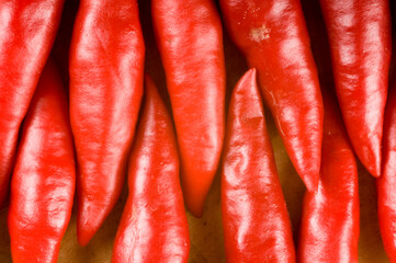 Bunch of red chilli peppers sitting end to end on a timber chopping board