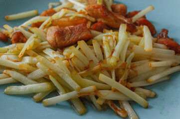 Stir-fried pork with leeks by yourself. Slightly charred fried meat and leeks on a blue plate, delicious food.