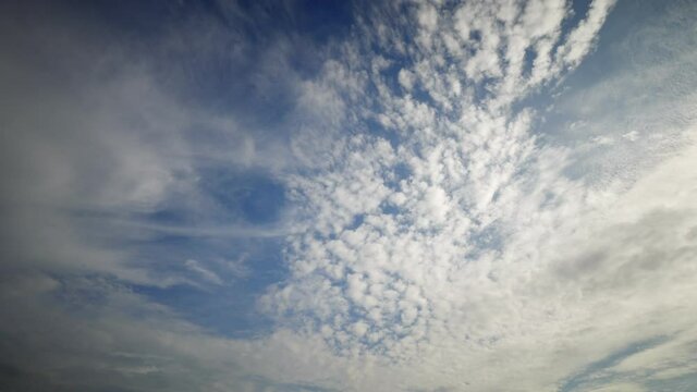 Various layers of clouds move in different directions at altitude, time lapse shot. Tropical sky at evening time, only white and blue colours