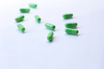 green pills on white background. Selective focus, blurred background
