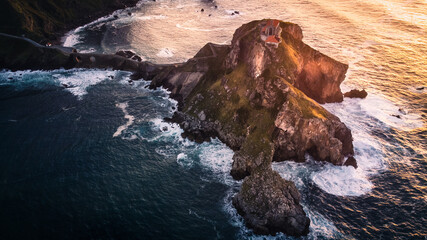 Islet of Gaztelugatxeko surrounded by incredible waves of the Atlantic ocean that crash on its...