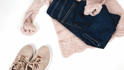 Pastel knitted sweater with denim pants, sneakers and accessories on a white background. Autumn and winter clothing. Shop, sale, fashion concept.