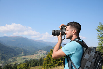 Professional photographer taking picture with modern camera in mountains. Space for text