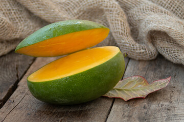 Ripe mango lies on a wooden textured table and was cut into two parts, levitation, rustic style
