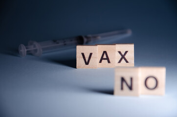 No vax concept. Anti-vaccination from coronavirus. Inscription No vax stands on blurred syringe background. Selective focus on Lettering No vax with copy space. Banner on blue background.