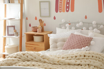 Comfortable bed with pillows and plaid in child's room. Interior design