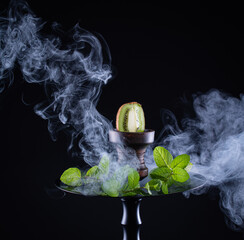 fruit hookah with tobacco, kiwi, mint and smoke on black background