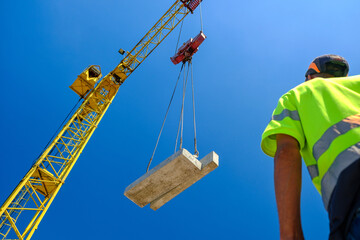 construction worker with crane. Hook cargo crane on the sky background. crane on a construction site - Powered by Adobe