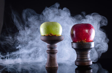 fruit hookah bowls with tobacco, two apple and smoke on black background