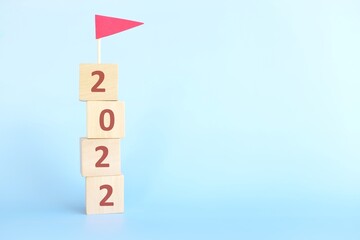 Year 2022 finish line, achievement, conclusion, review, summary and finishing annual report concept. Building blocks with 2022 number and red flag in blue background.