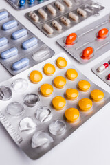 Heap of medical pills in white, yellow, orange and other colors. Plastic package with pills. Concept of healthcare and medicine.